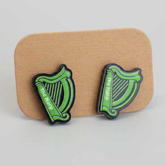 Green and black harp-shaped earrings on a cardboard backing.